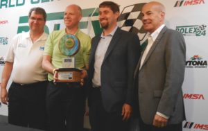 from left, Tim Mellon (SAE), Karl J. Simon (EPA), Michael Carr (DOE) and Scott Atherton (IMSA) pose with new IMSA Green Racing trophy.